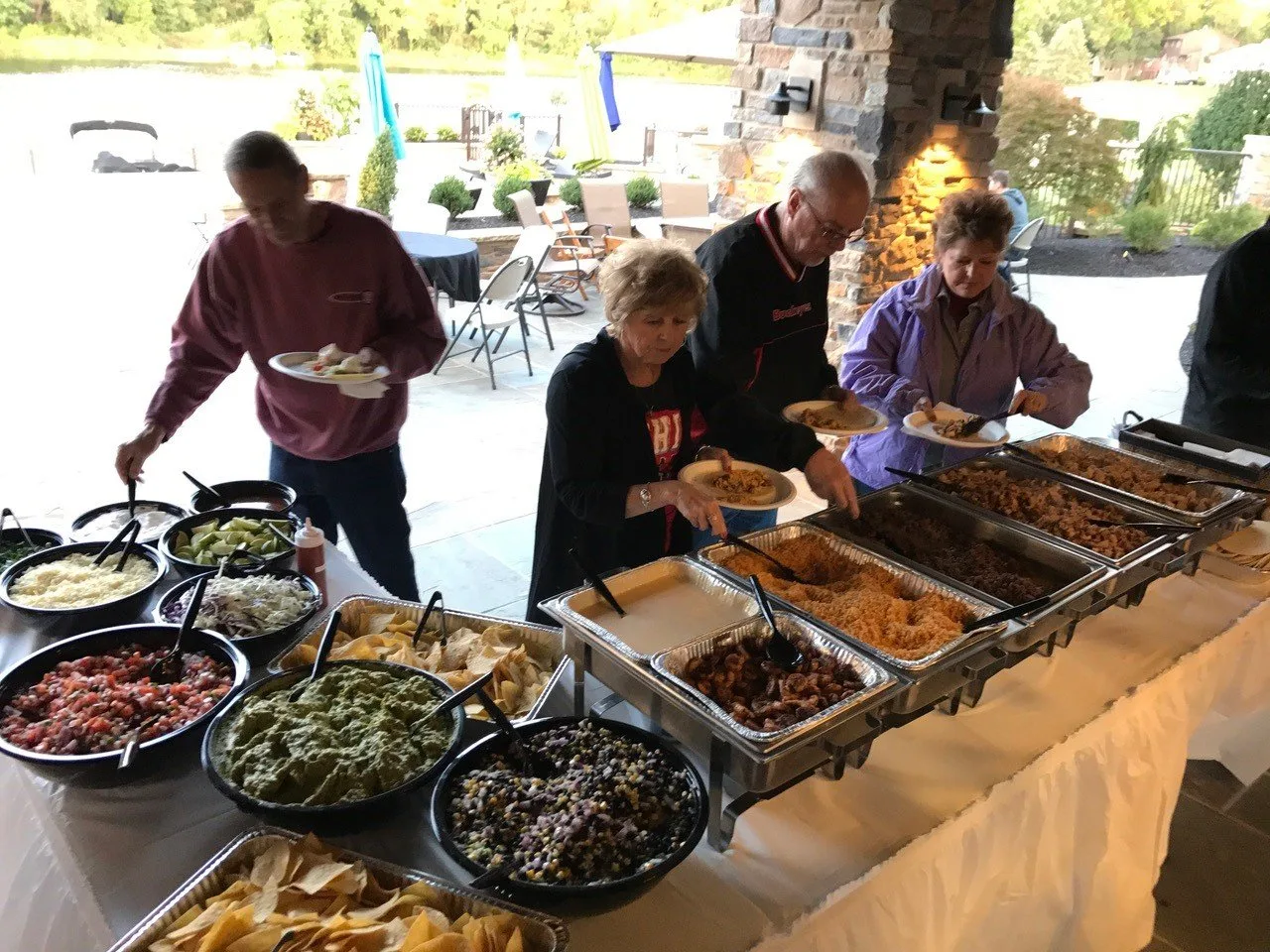 An outdoor catering buffet line with chafing trays and fresh toppings
